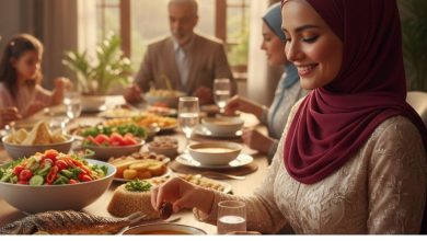 امرأة محجبة تبتسم وهي تفطر بالتمر والماء على مائدة رمضانية صحية مليئة بالسلطة والشوربة والفواكه، مع عائلتها في أجواء دافئة